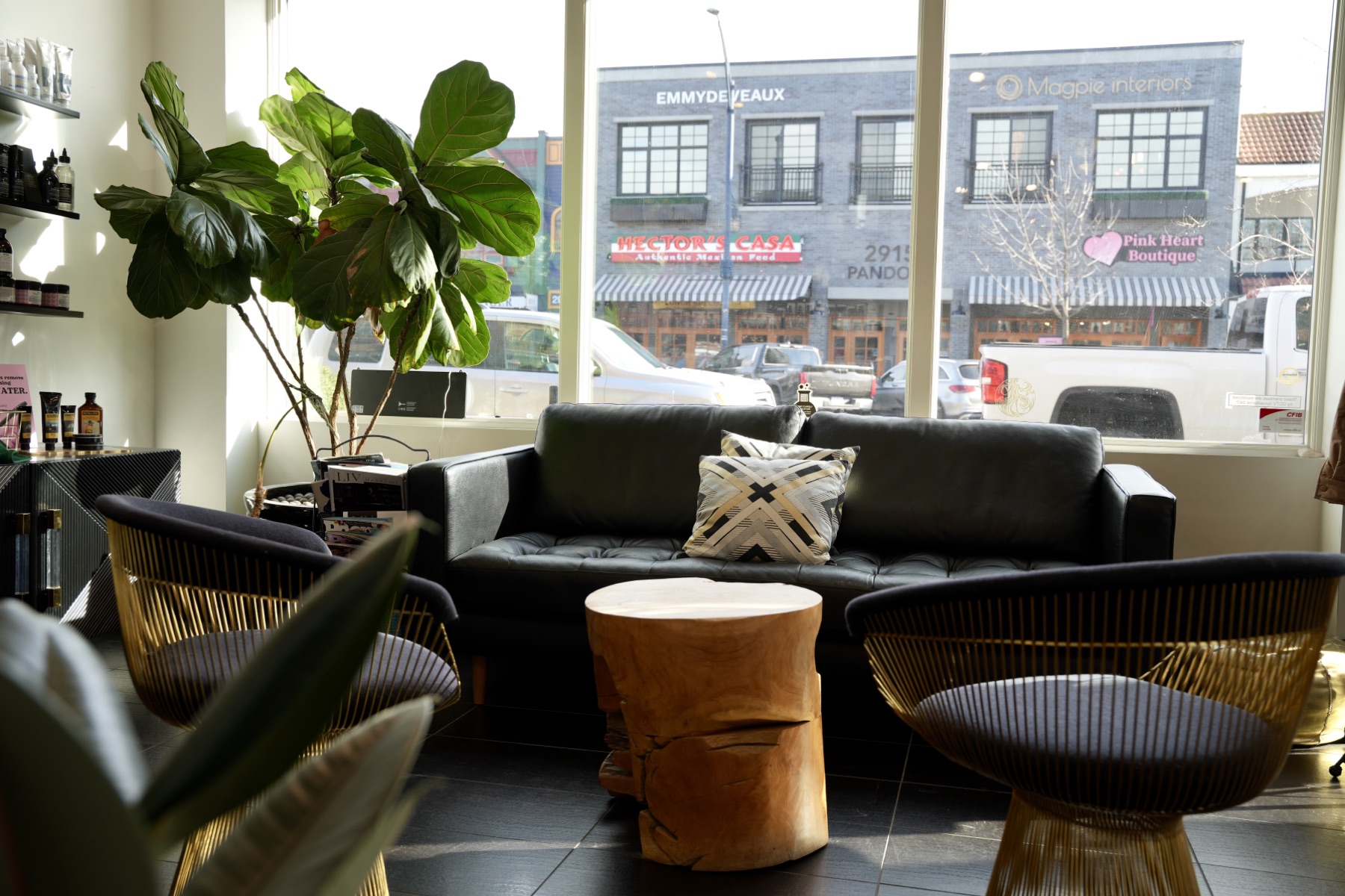 Best Kelowna Hair Salon: Guest lounge with a leather sofa and gold chairs by the front windows