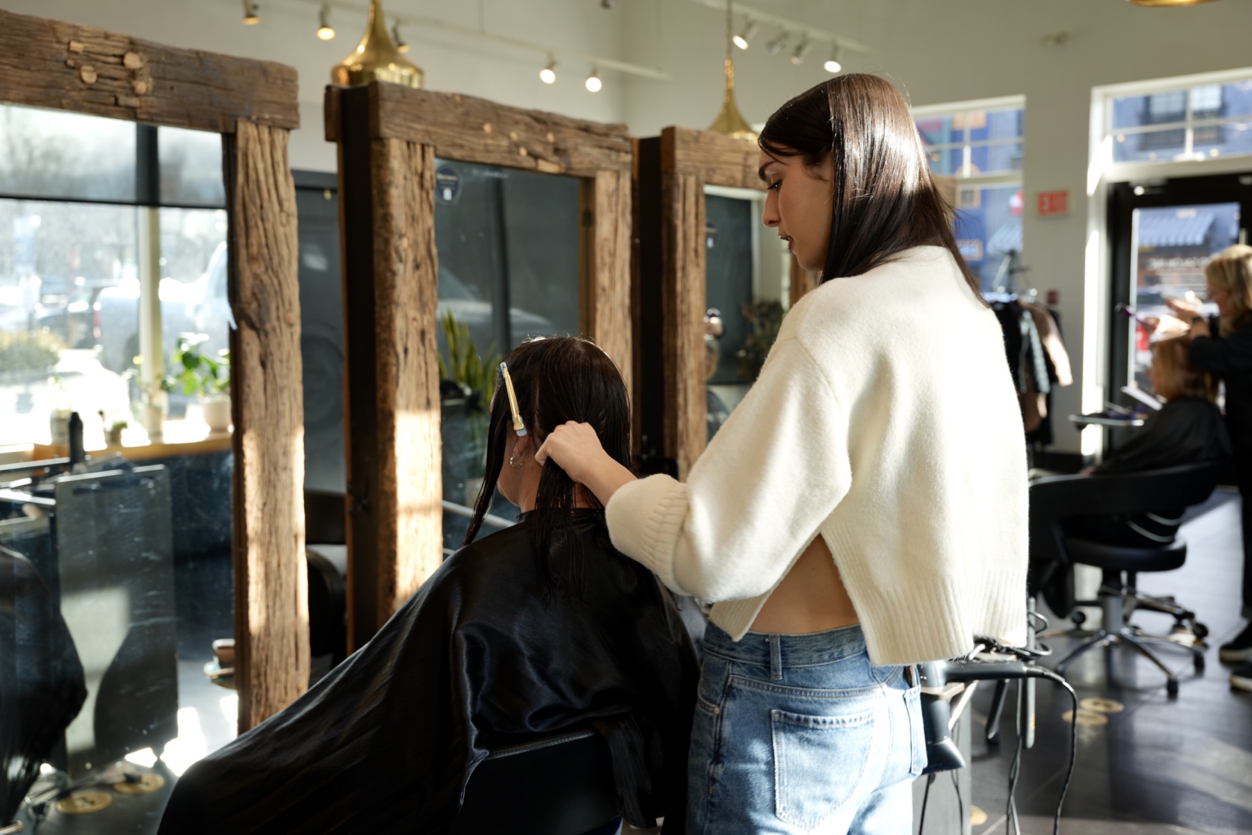 Best Kelowna Hair Salon: Stylist cutting a client’s hair at a wood-framed mirror
